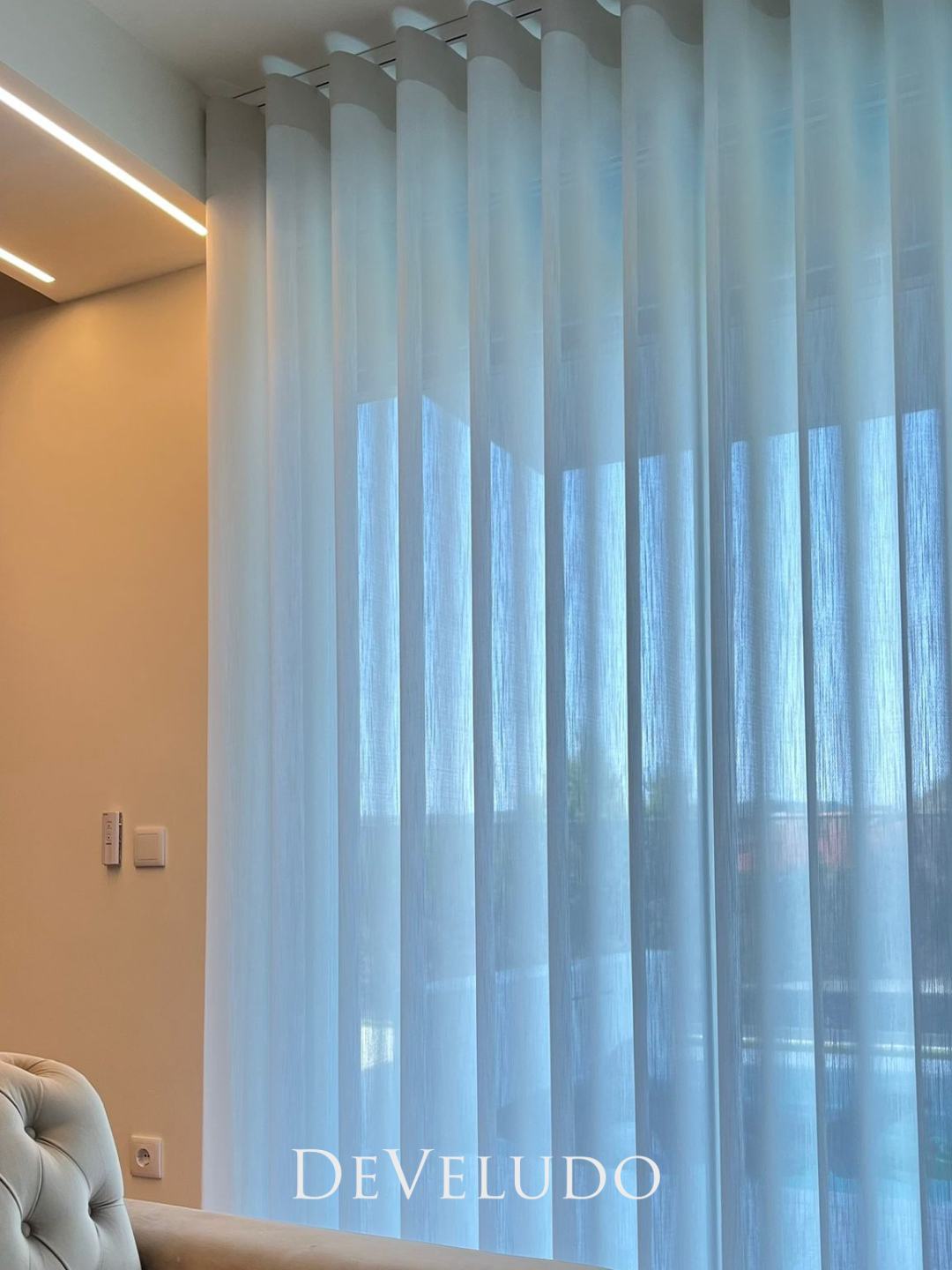 Cortinado de onda diante de um envidraçado, com luz azulada do exterior