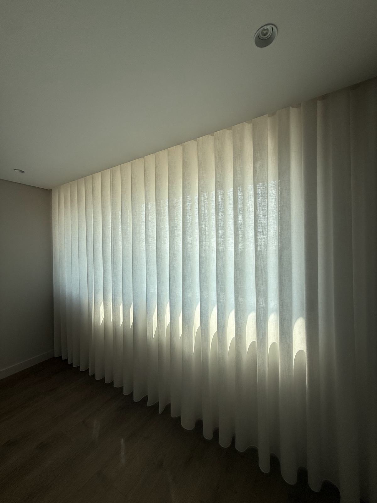 Cortinado de onda com luz rasante a marcar cada prega do tecido