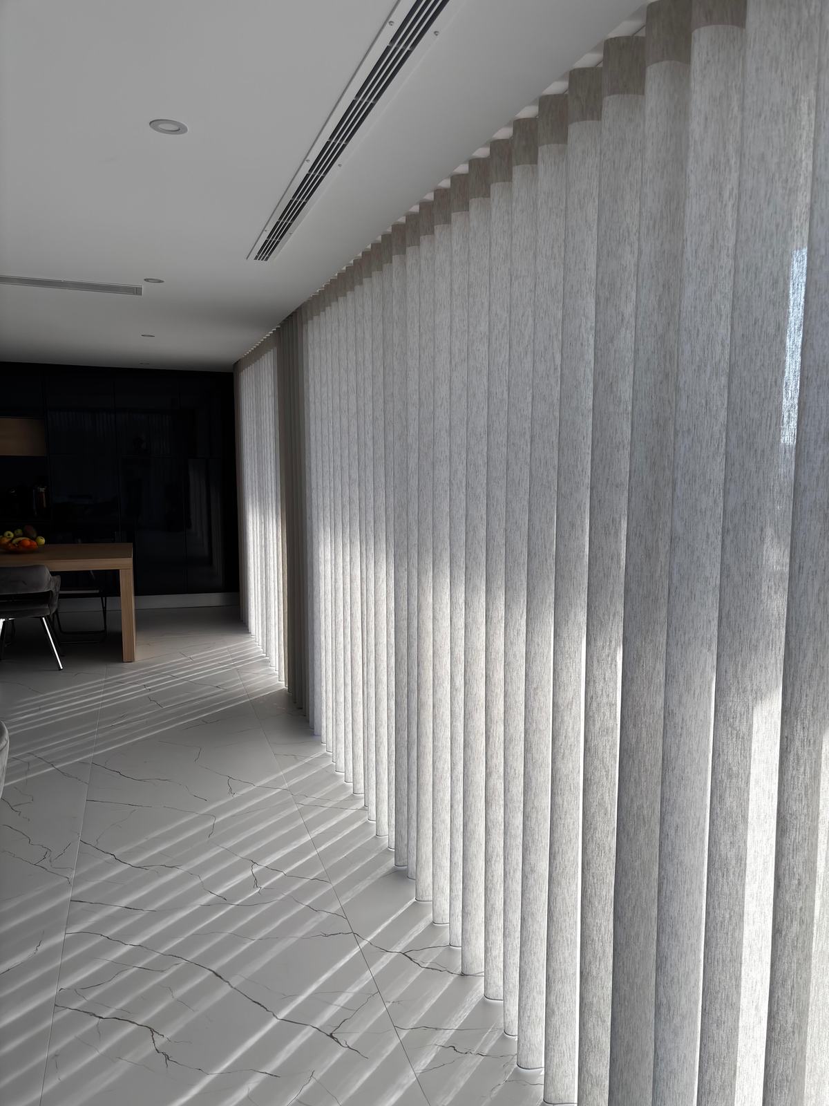 Cortinado de onda a cobrir uma parede inteira, com a luz a desenhar vincos no chão