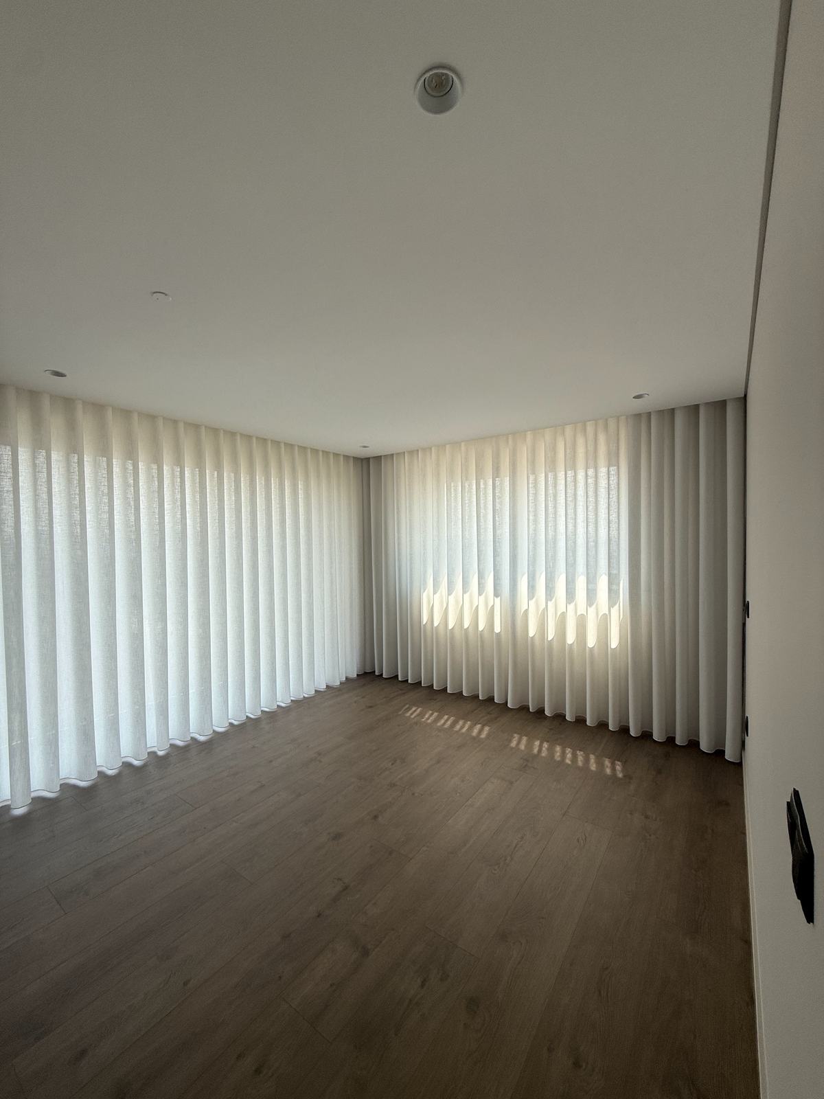Divisão com cortinados de onda e o desenho do sol projetado no soalho