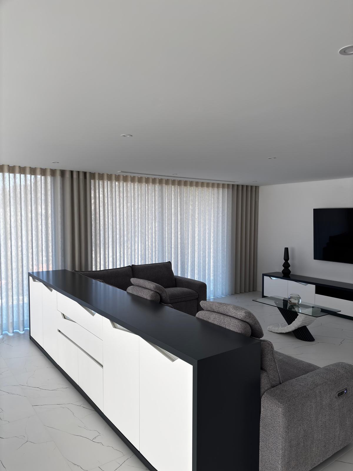 Sala de estar com televisão e cortinados de onda em tom areia