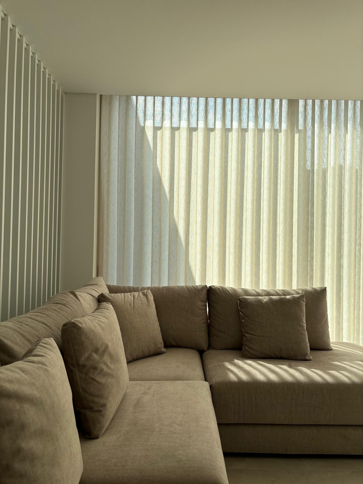 Sala de estar com sofá de chaise longue e cortinados de onda em toda a parede